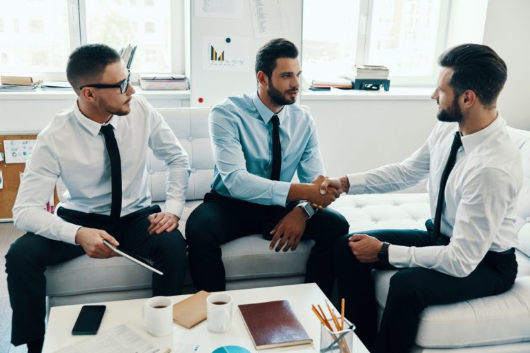 Mutual understanding. Young modern men in formalwear shaking hands while working in the office